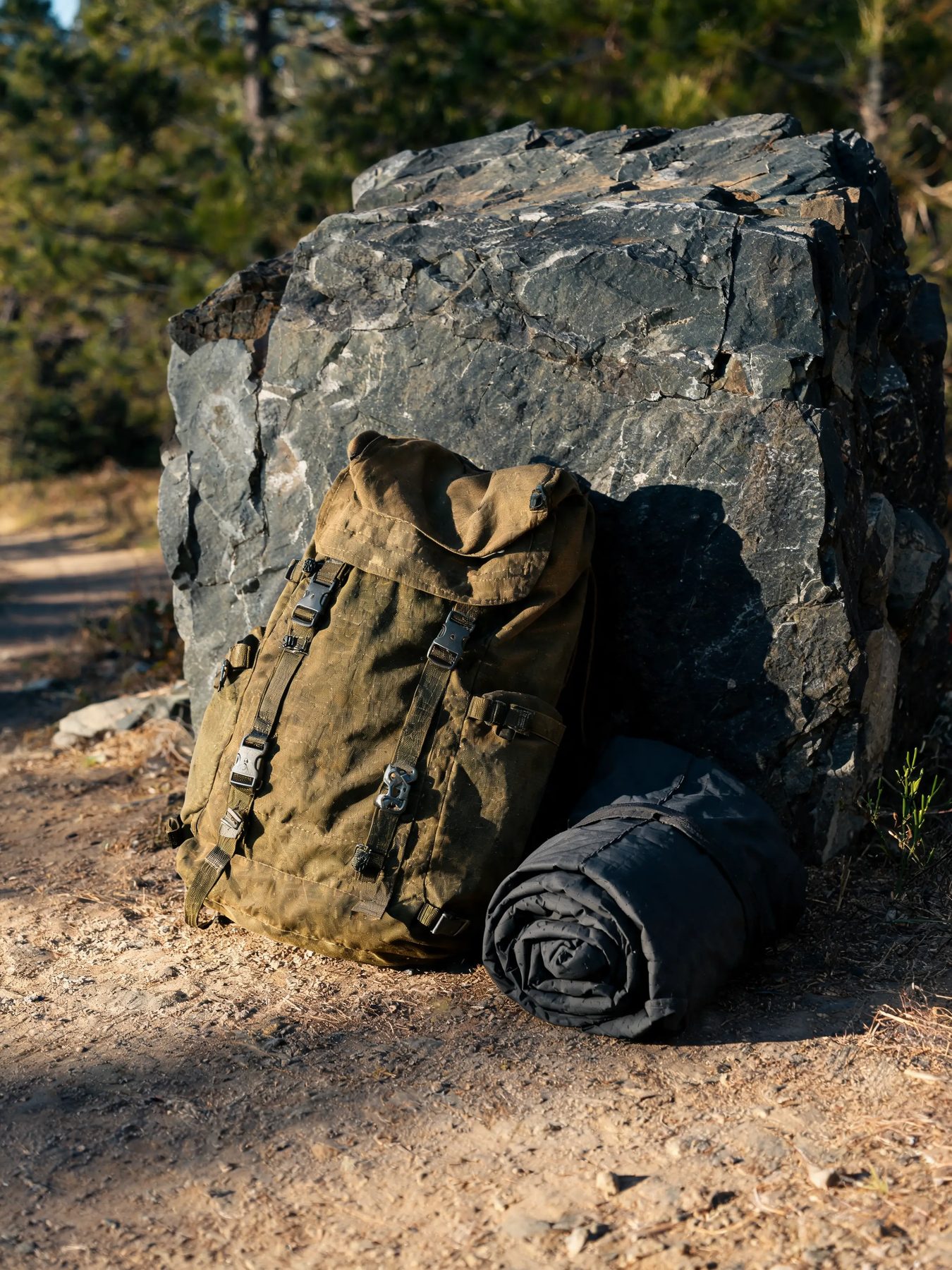 Ripstop daypack and rolled shell jacket against a slate boulder